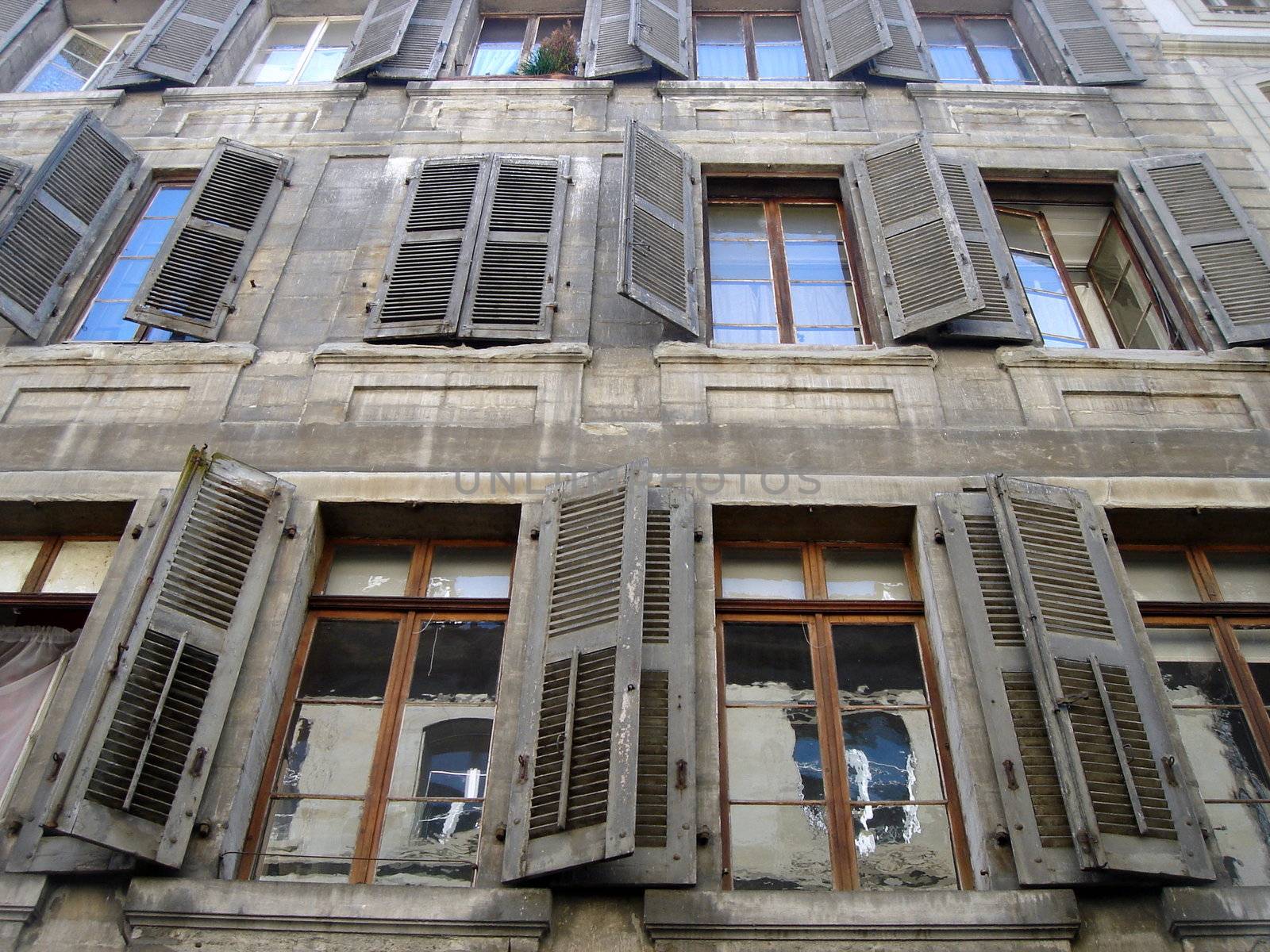 Old windows with old shutters on the polluted facade of a building