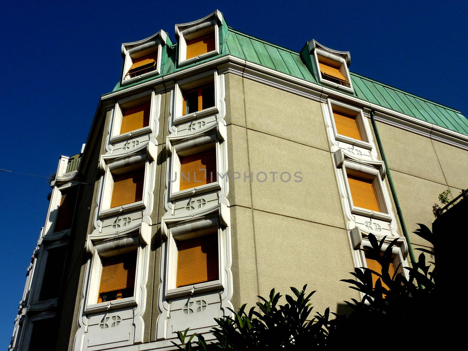 Original facade of a building with green roof and yello windows by beautiful weather