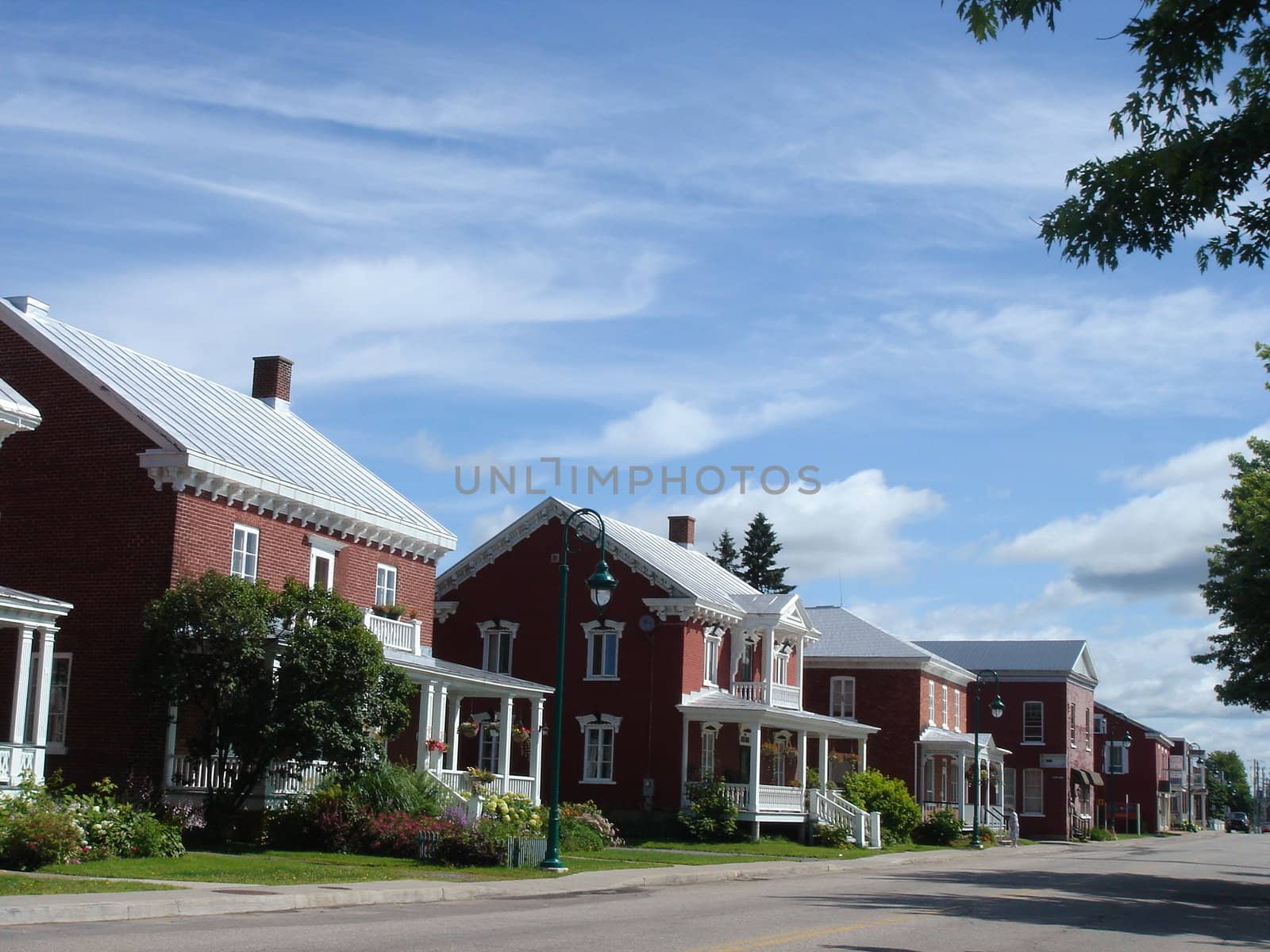 Street of Yamachiche with historical red houses, Quebec, Canada, by cloudy weather