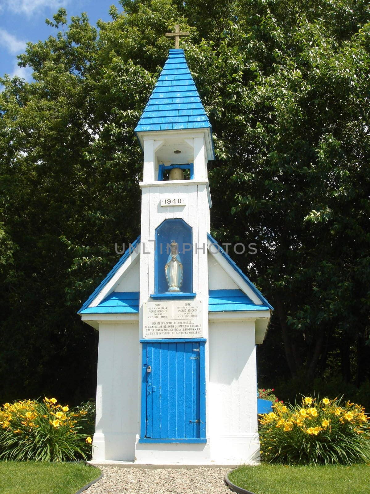 Small white and green chapel surrounded by trees