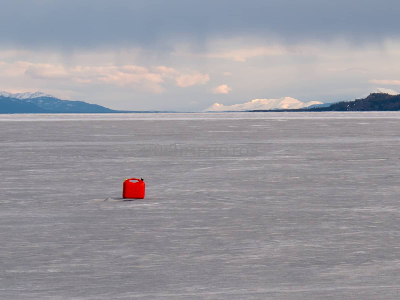 Red jerry-can full of gasoline on vast frozen Lake Laberge, Yukon Territory, Canada