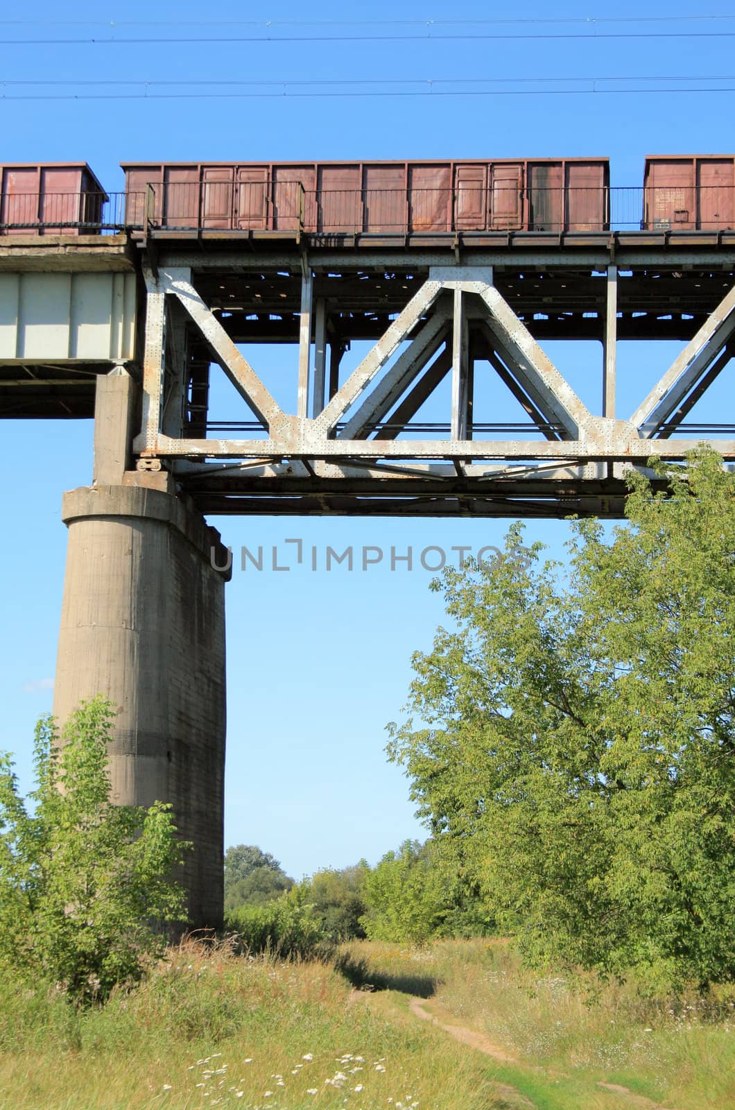 Freight train passing the steel bridge over the river
