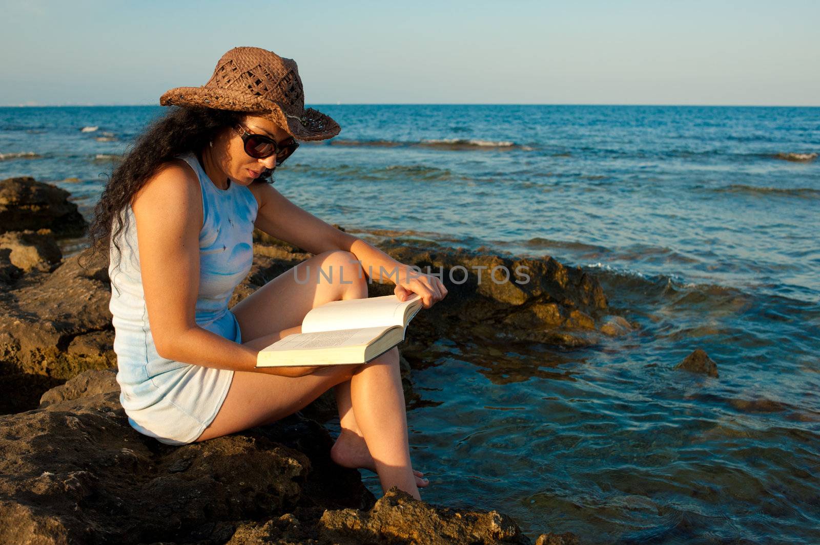 Woman ejoying a book with her feet in the water