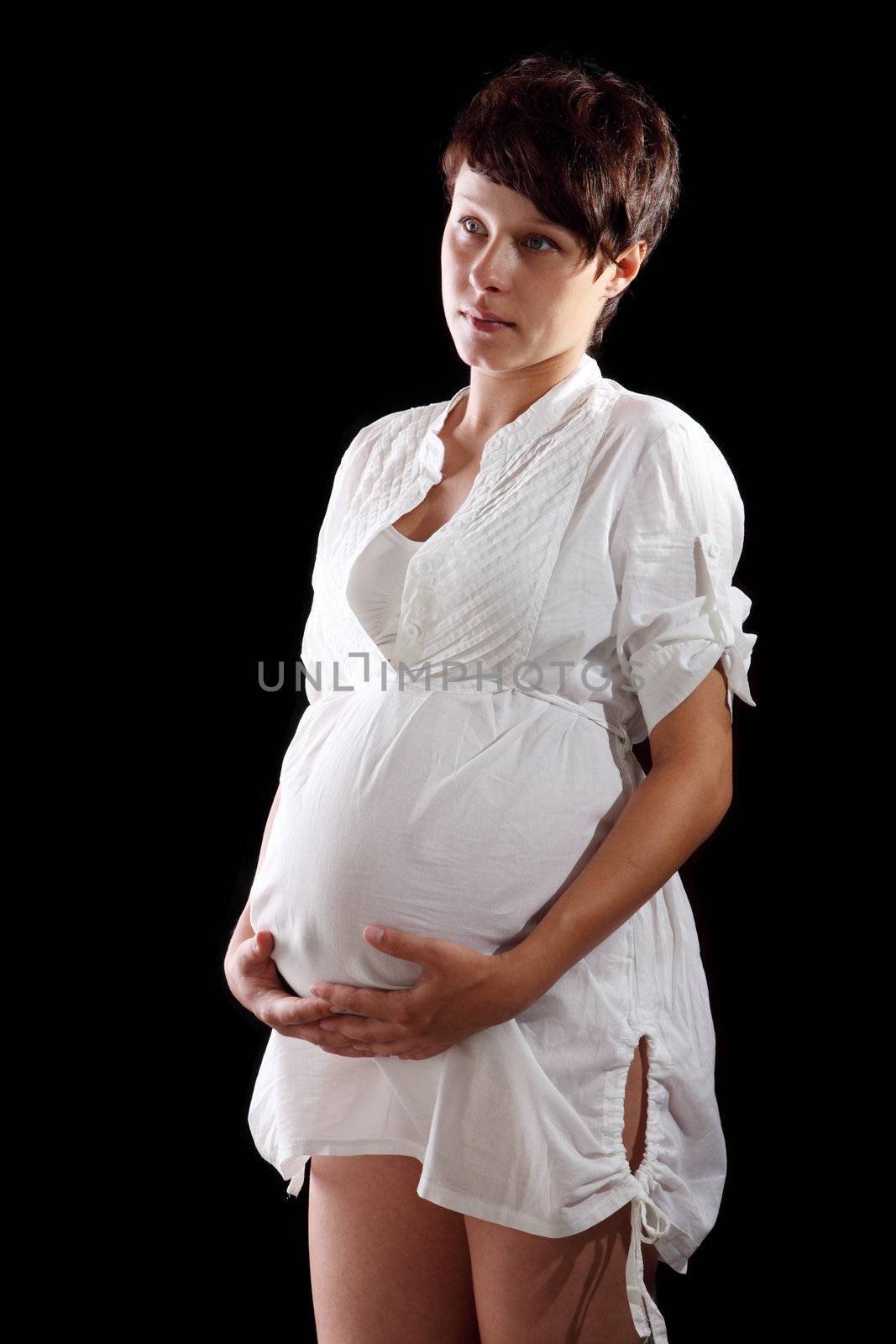 Pregnant young woman in a white shirt on the black background
