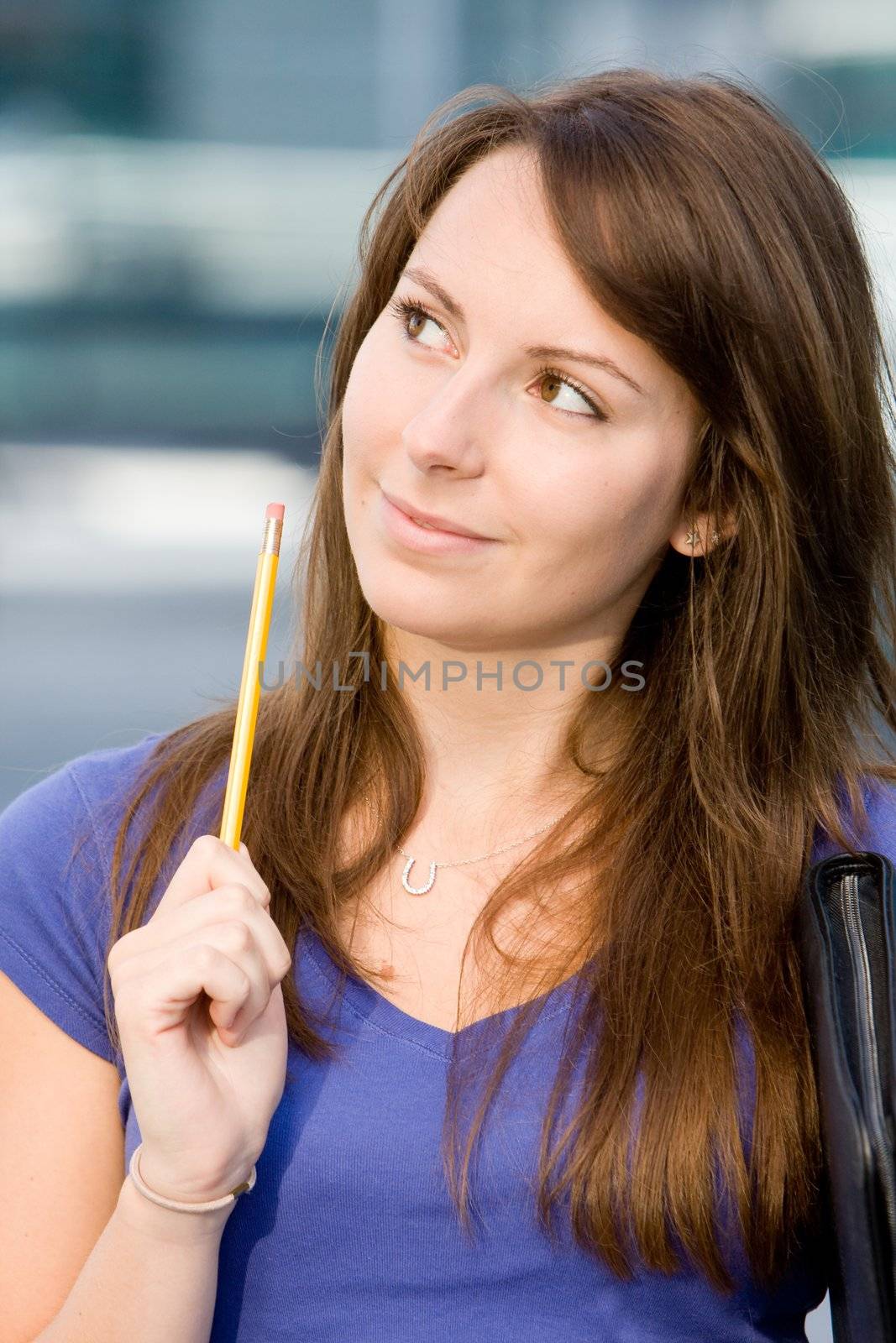 Pretty beautiful caucasian white girl pondering or thinking outside college school holding pencil
