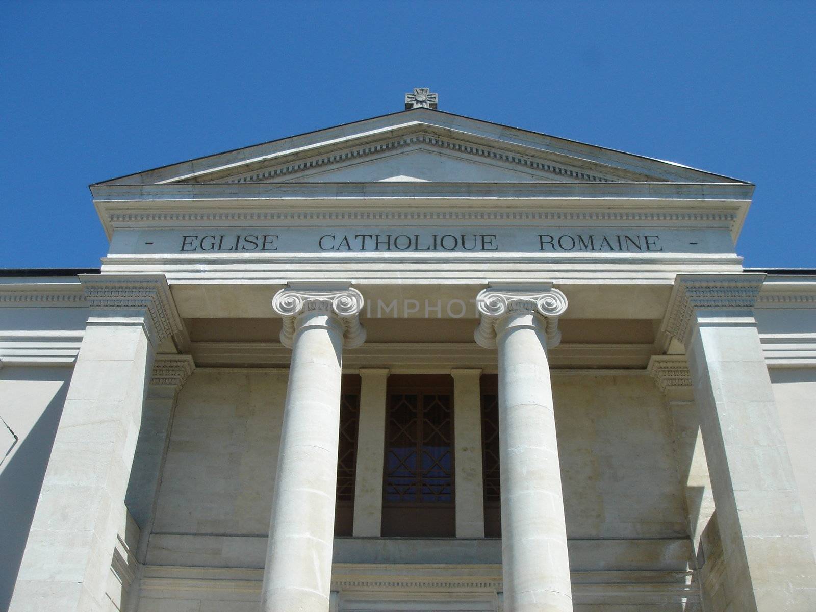 Facade of a white roman catholic church with pylons by sunny day.