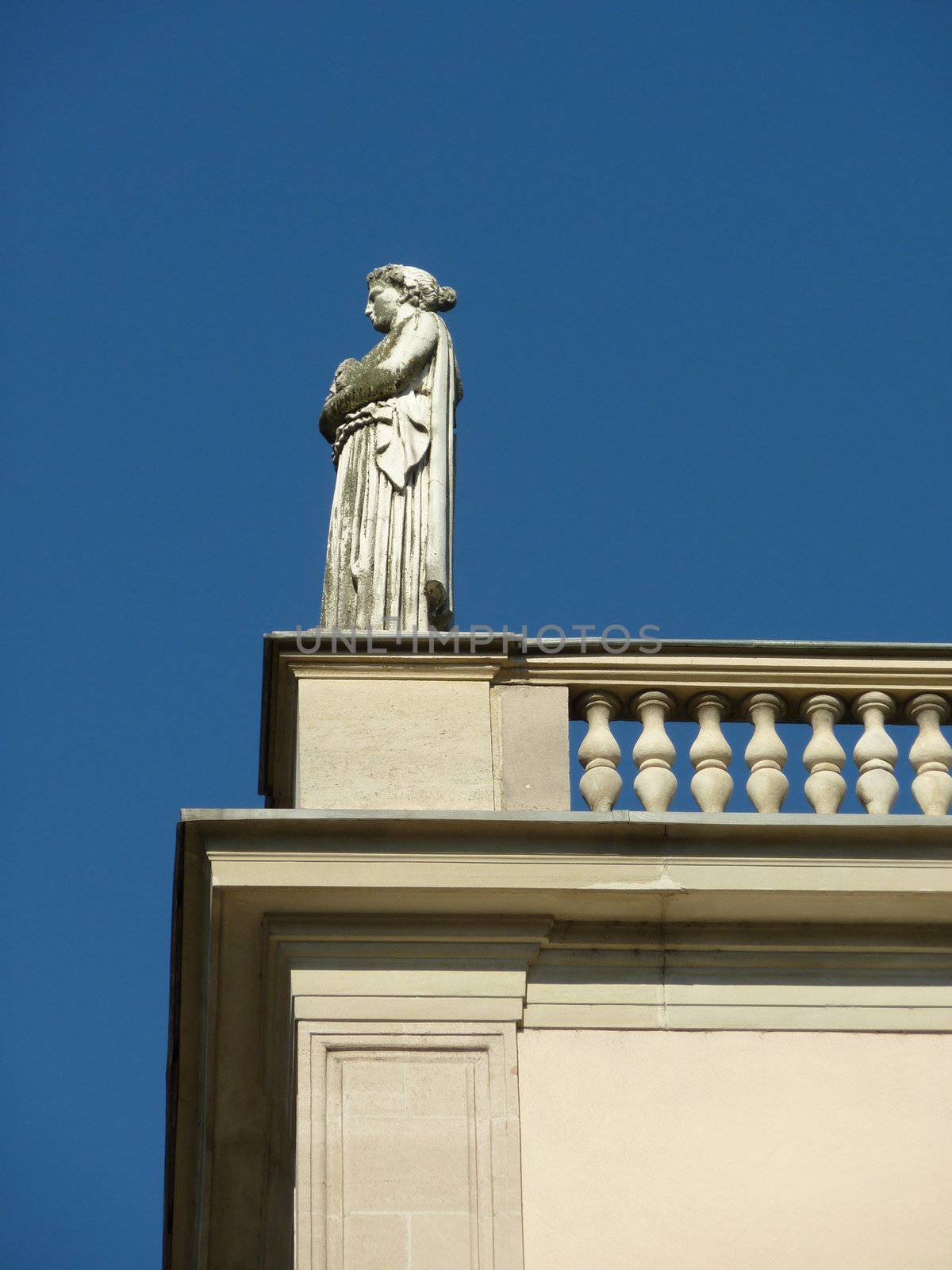 White statue of a woman on a balcony looking on the left
