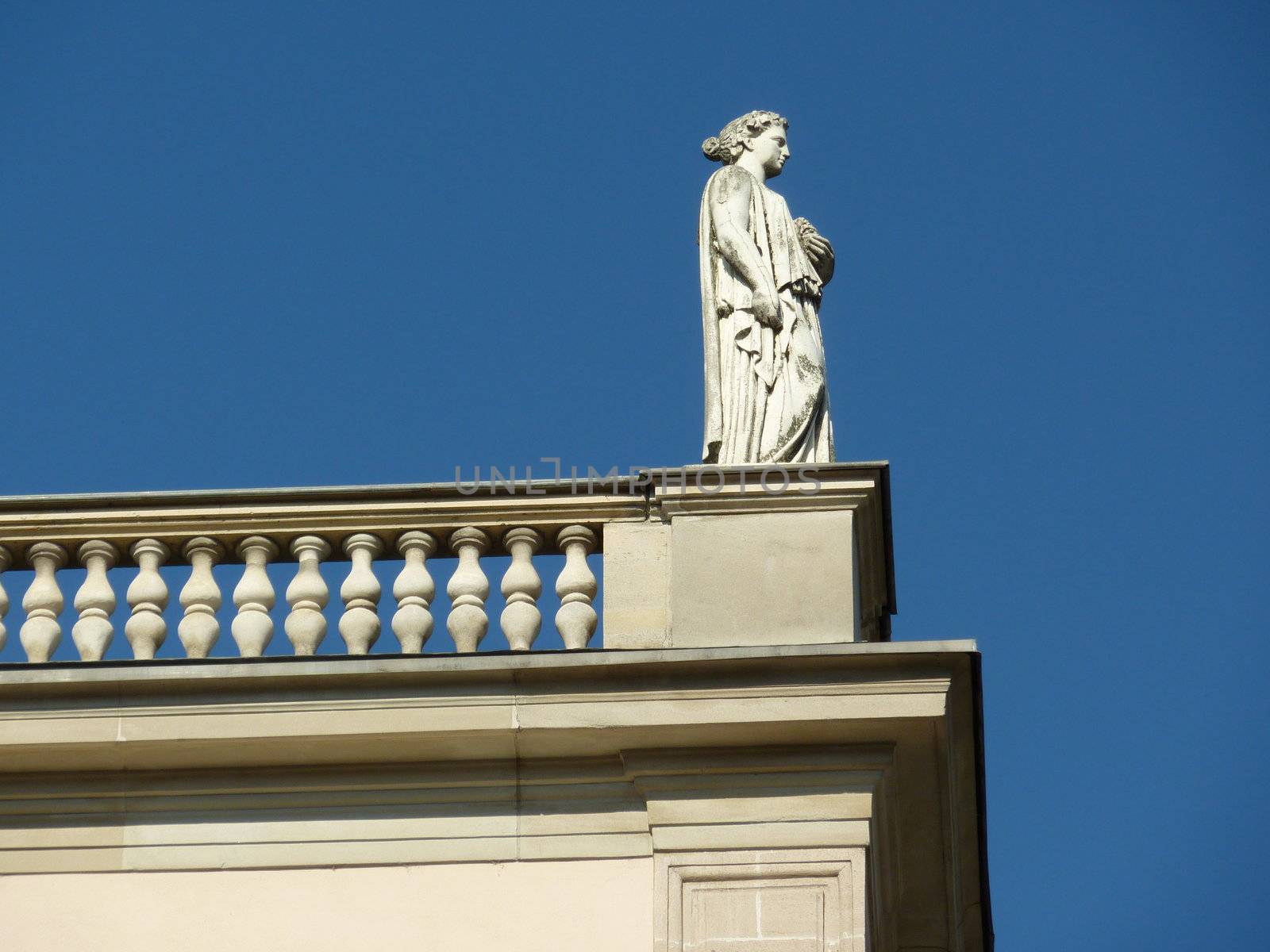 White statue of a woman on a balcony looking on the right