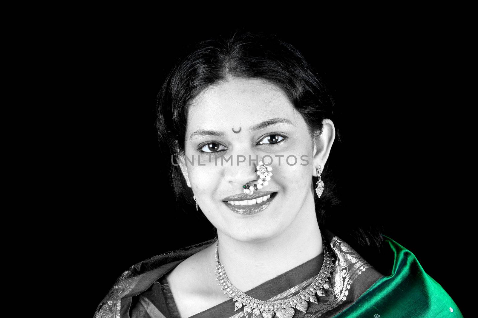 A portrait of a beautiful east Indian woman in a green sari, on black studio background.