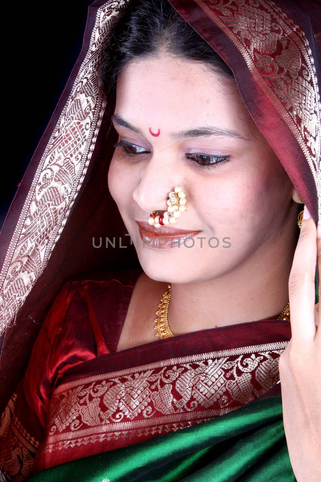 A beautiful Indian woman wearing a green sari covering her head traditionally, on the occasion of a festival.