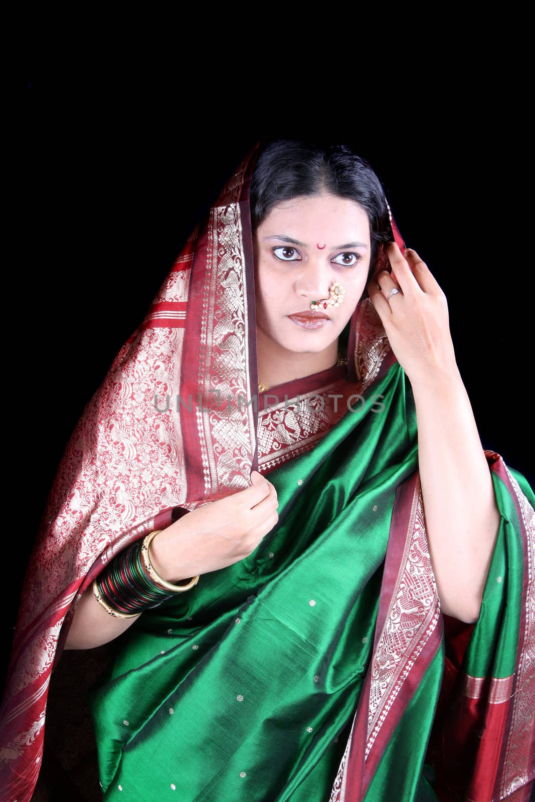 A portrait of a traditional Indian lady expressing anger, on black studio background.