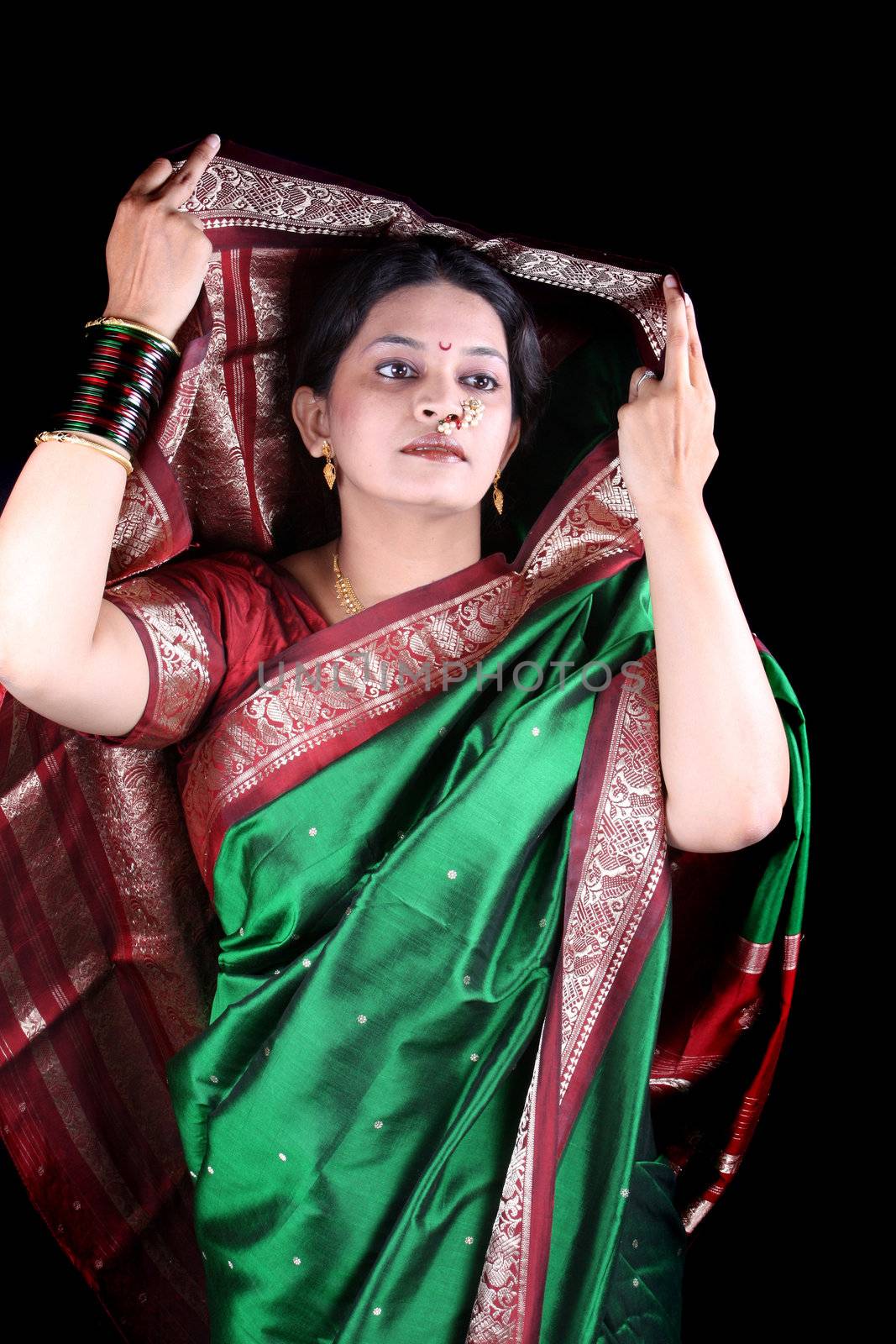 An Indian woman wearing her traditional green sari, on black studio background.