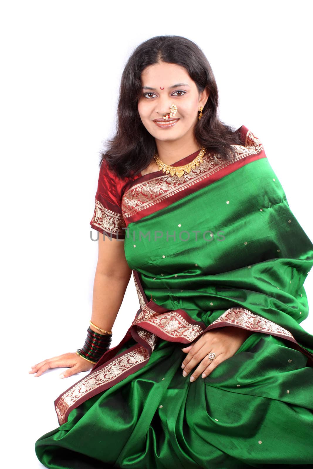 A smiling beautiful woman in traditional Indian sari, on white studio background.