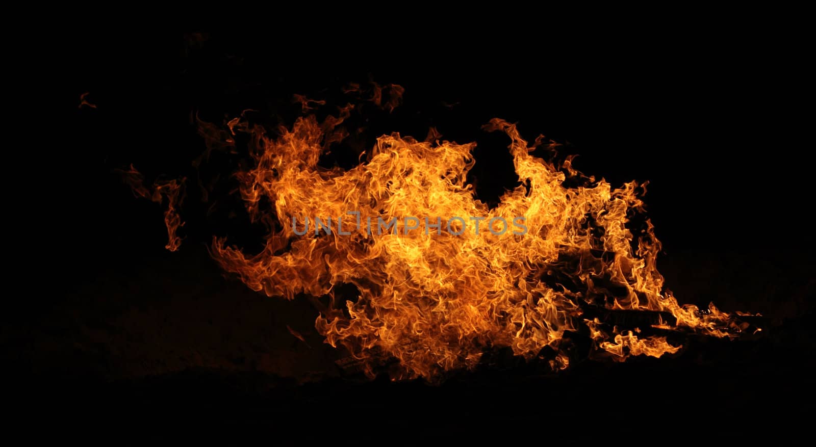 A raging bonfire burns on the beach.
