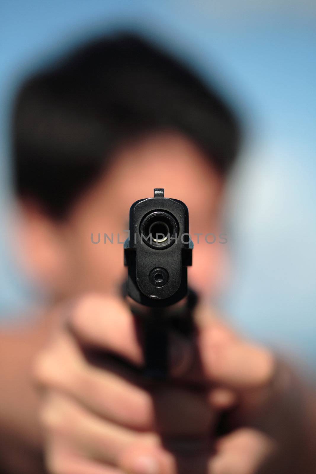 A young, robust man, in his 20's with dark hair pointing 2 pistols to the camera.