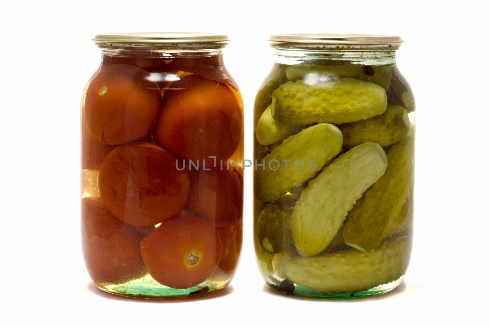 two glass jars with preserved tomatoes and cucumbers, isolated on white