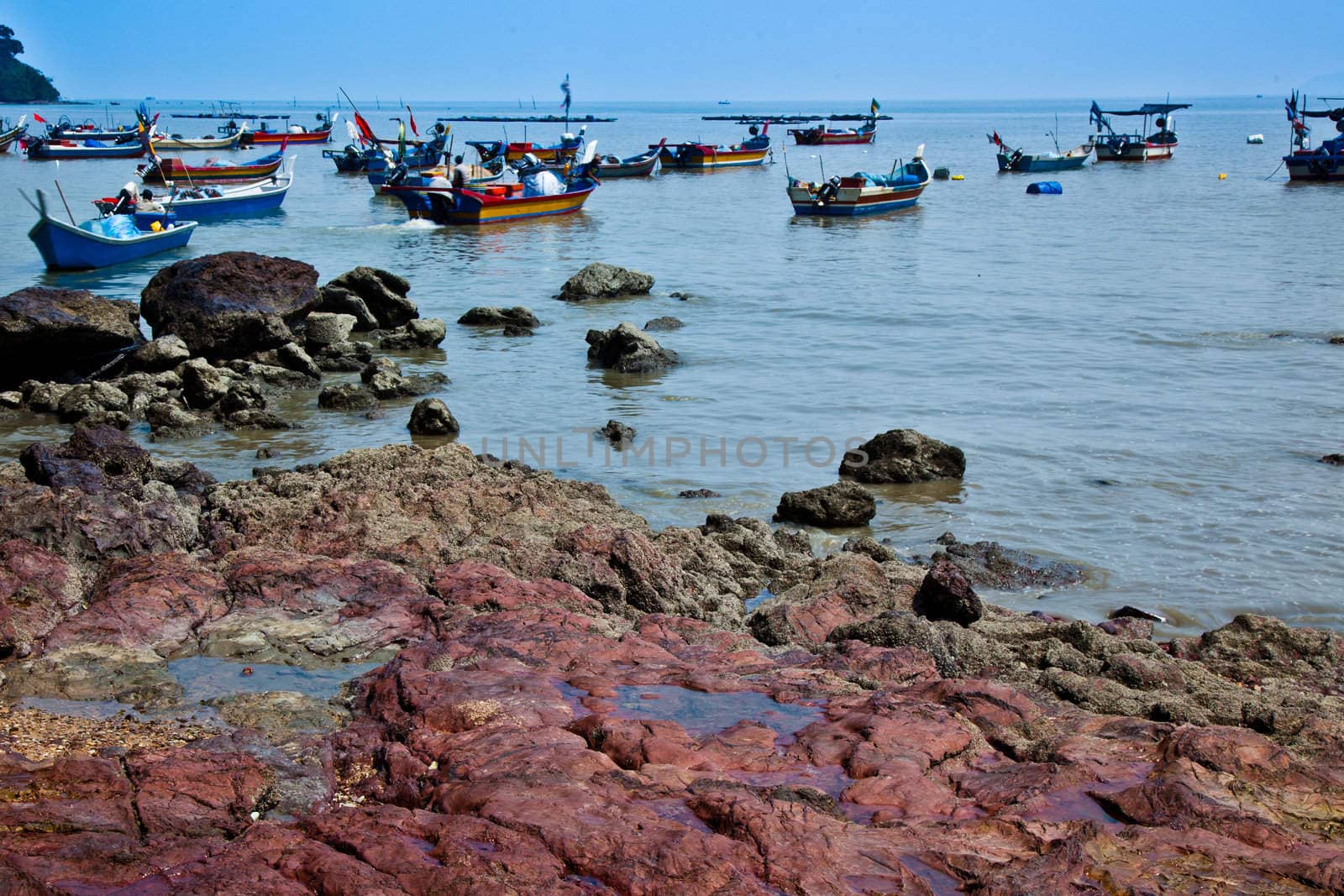 A view of Malaysian fishing boats with rock formations in the foreground