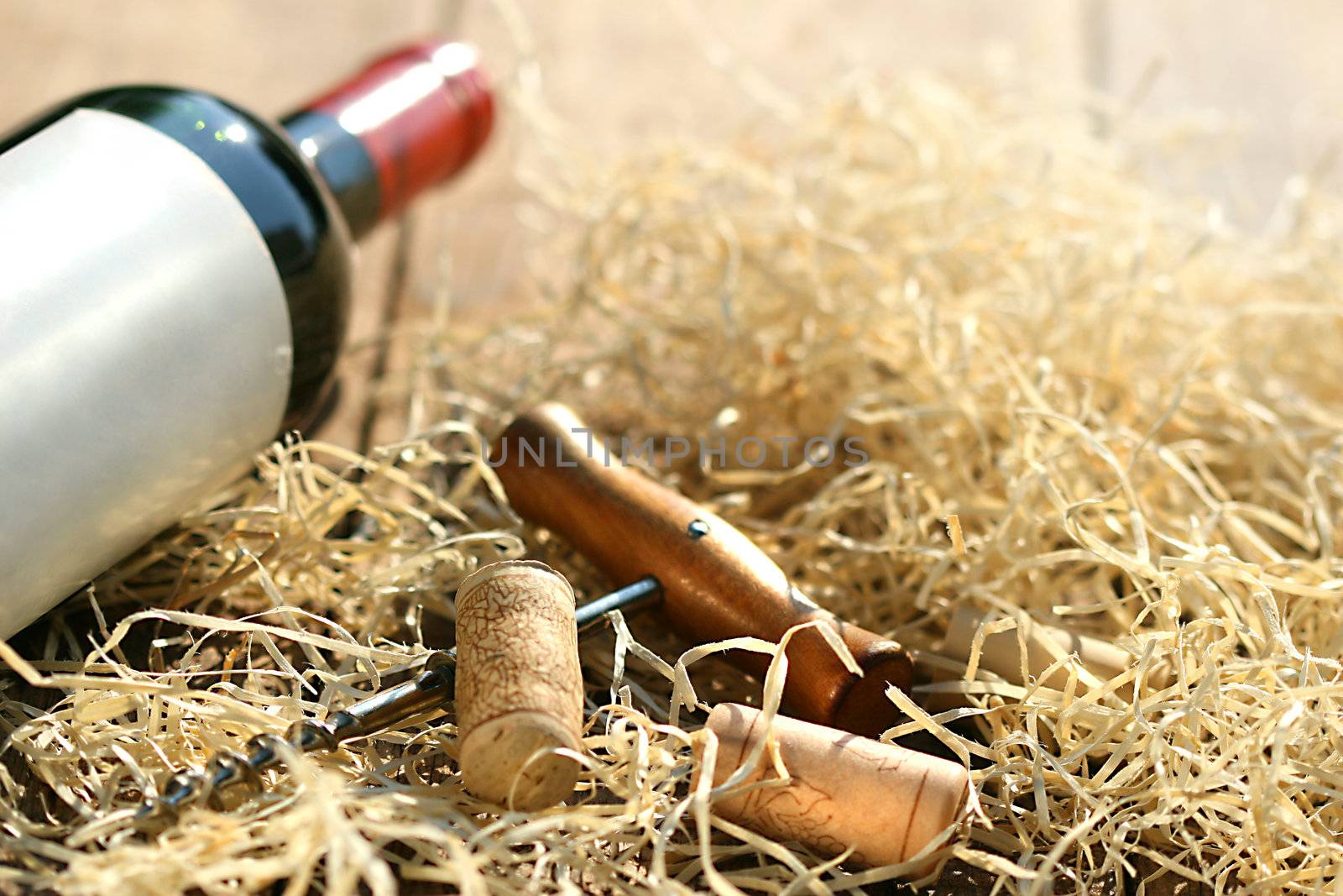 Bottle of red wine with corkscrew and packing straw