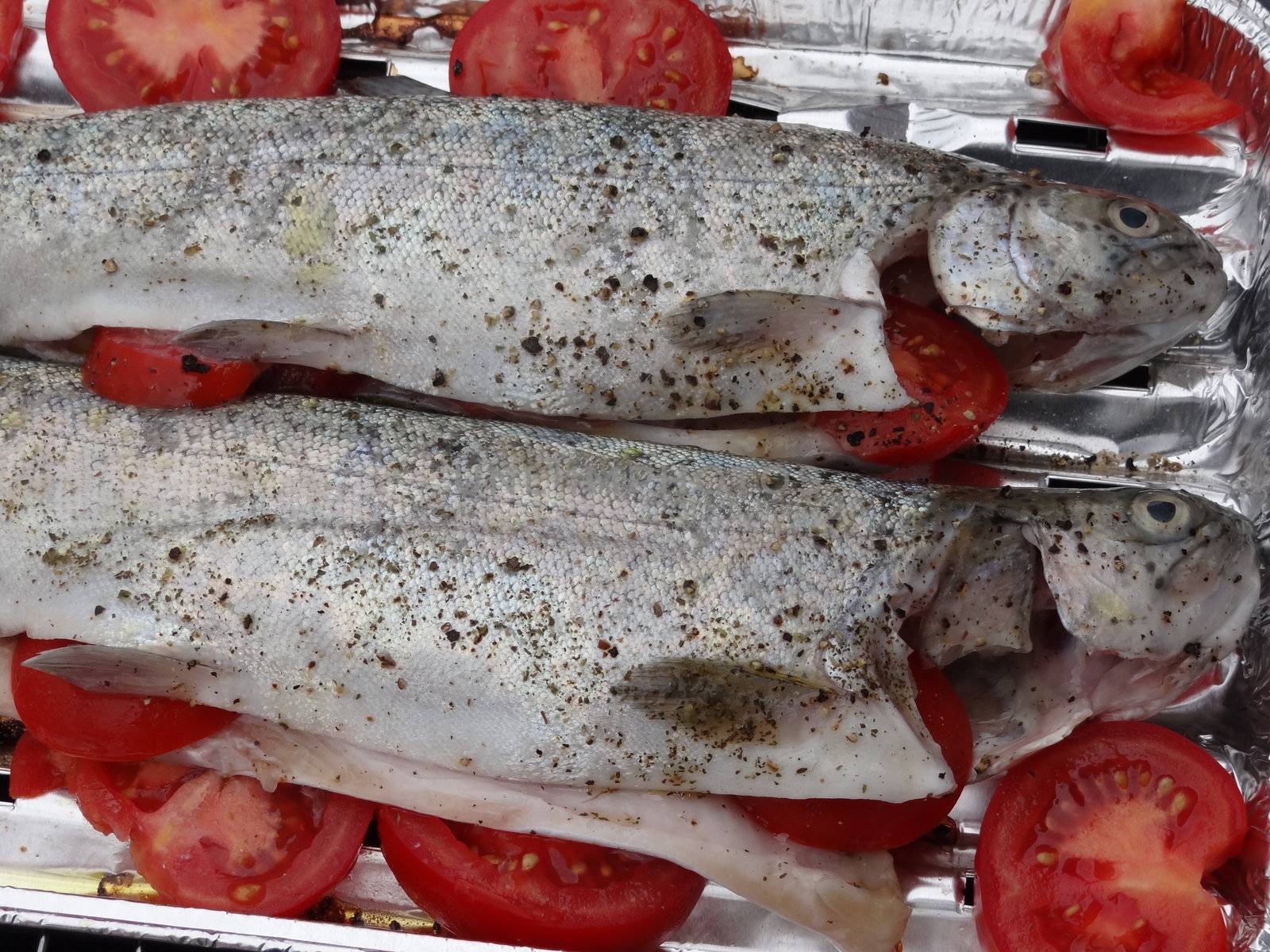 Two rainbow trouts on grill with tomatoes