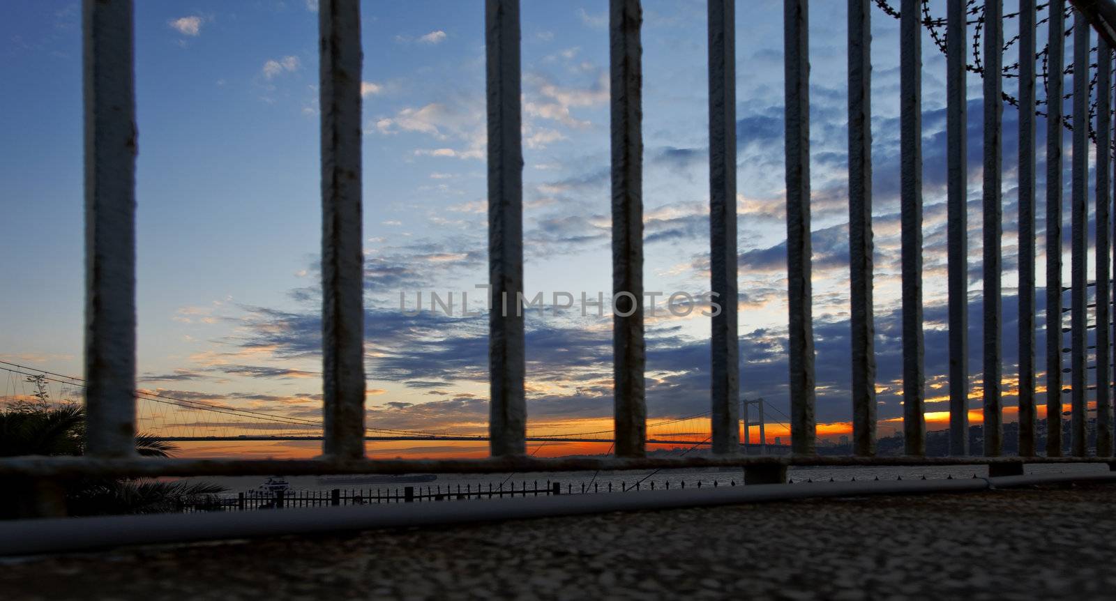 sunset over the bosphorus river and Bogazici Kpr Bridge Istanbul viewed through railings and barbed wire, landscape, crop space, copy space