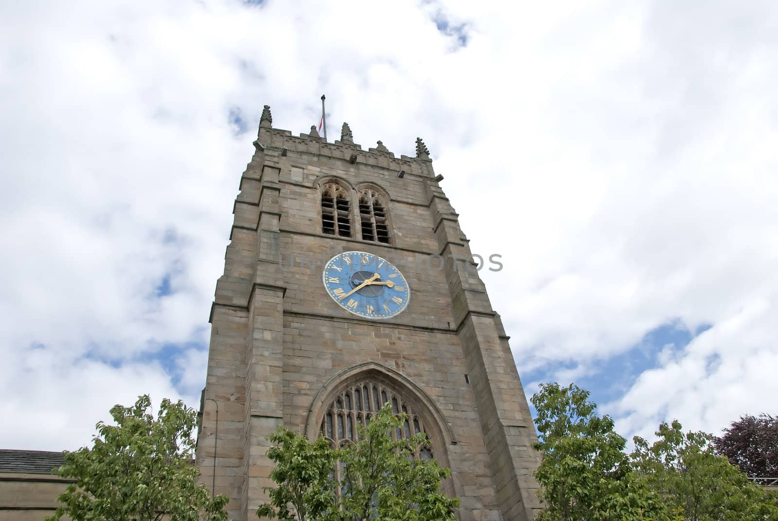 An English Cathedral Clocktower showing a blue and gold clock