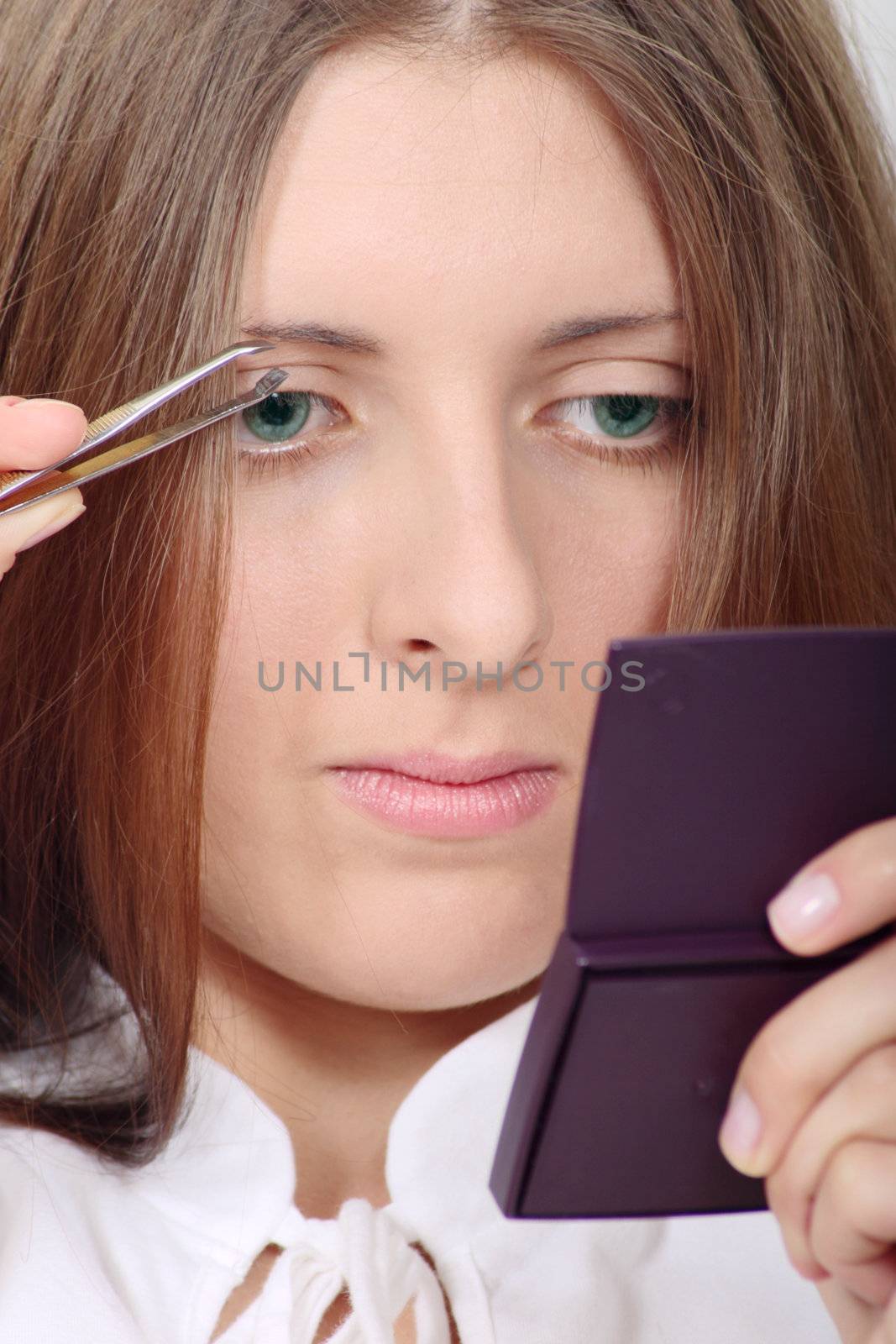 The attractive girl engaged in plucking out of eyebrows