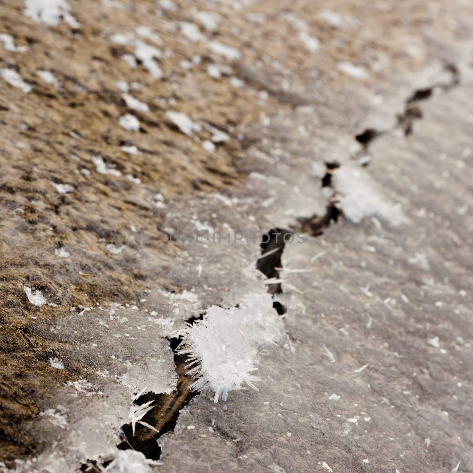 Cracked thick layer of ice with hoar-frost ice crystals forming on edge.