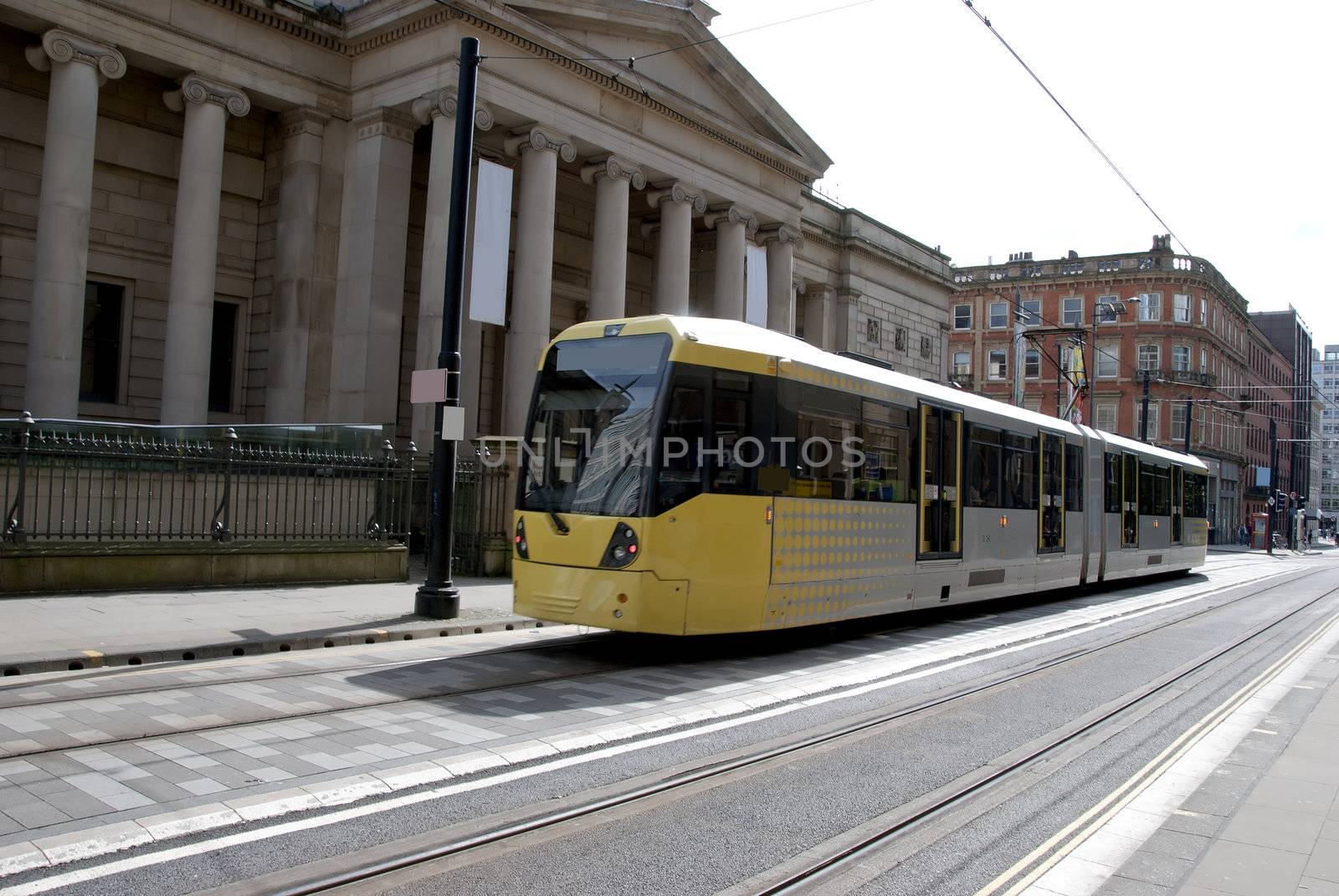 A Modern Yellow Tramcar passing an old Art Gallery in a city street