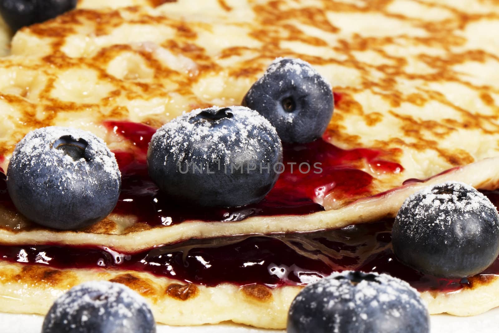 closeup of sugar covered blueberries with jam on pancakes