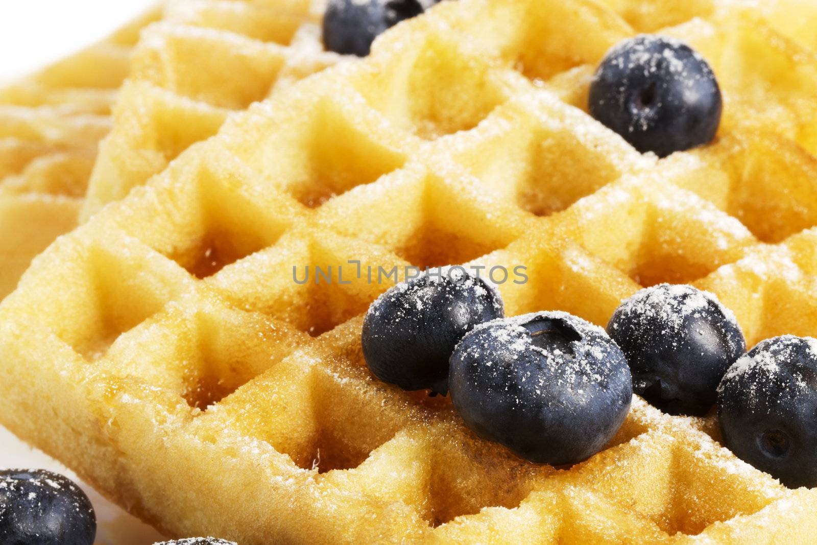 closeup from waffels with sugar covered blueberries and syrup