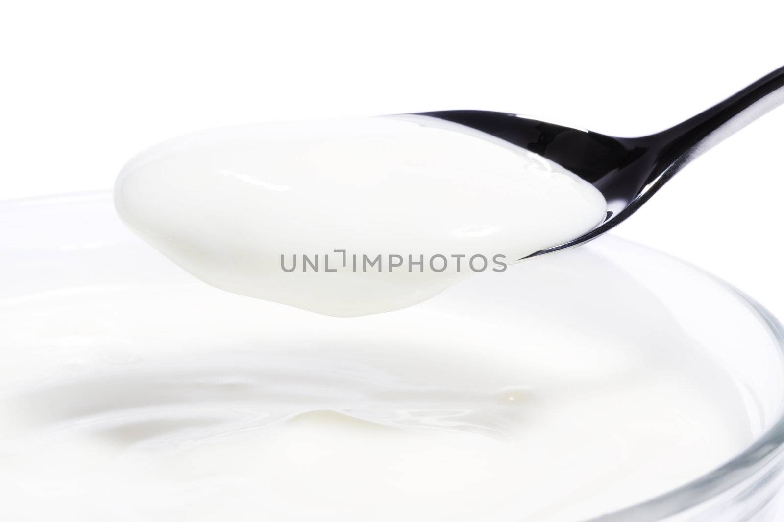 yogurt on a spoon over a yogurt dessert on white background