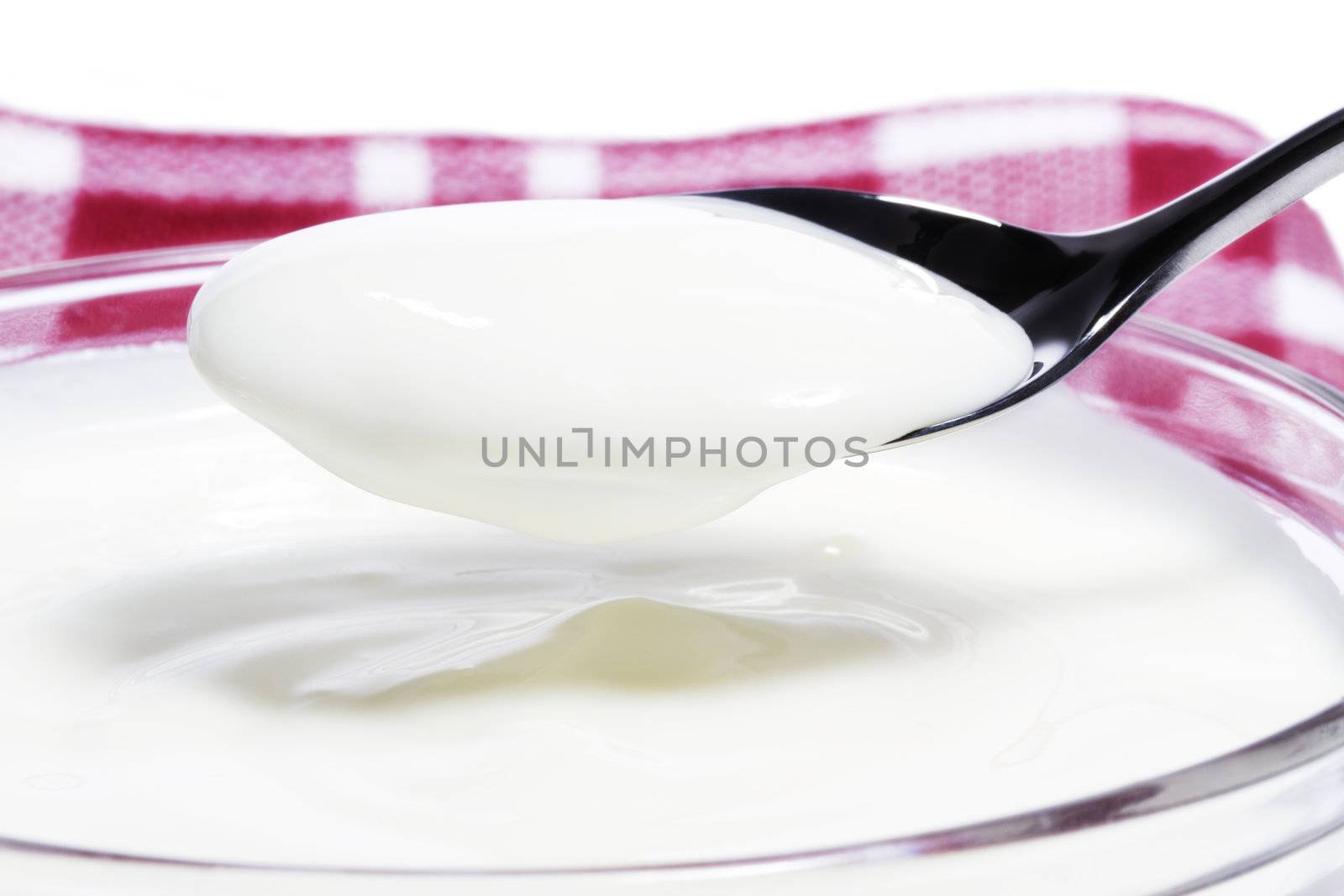 yogurt on a spoon over a yogurt dessert on a towel on white background