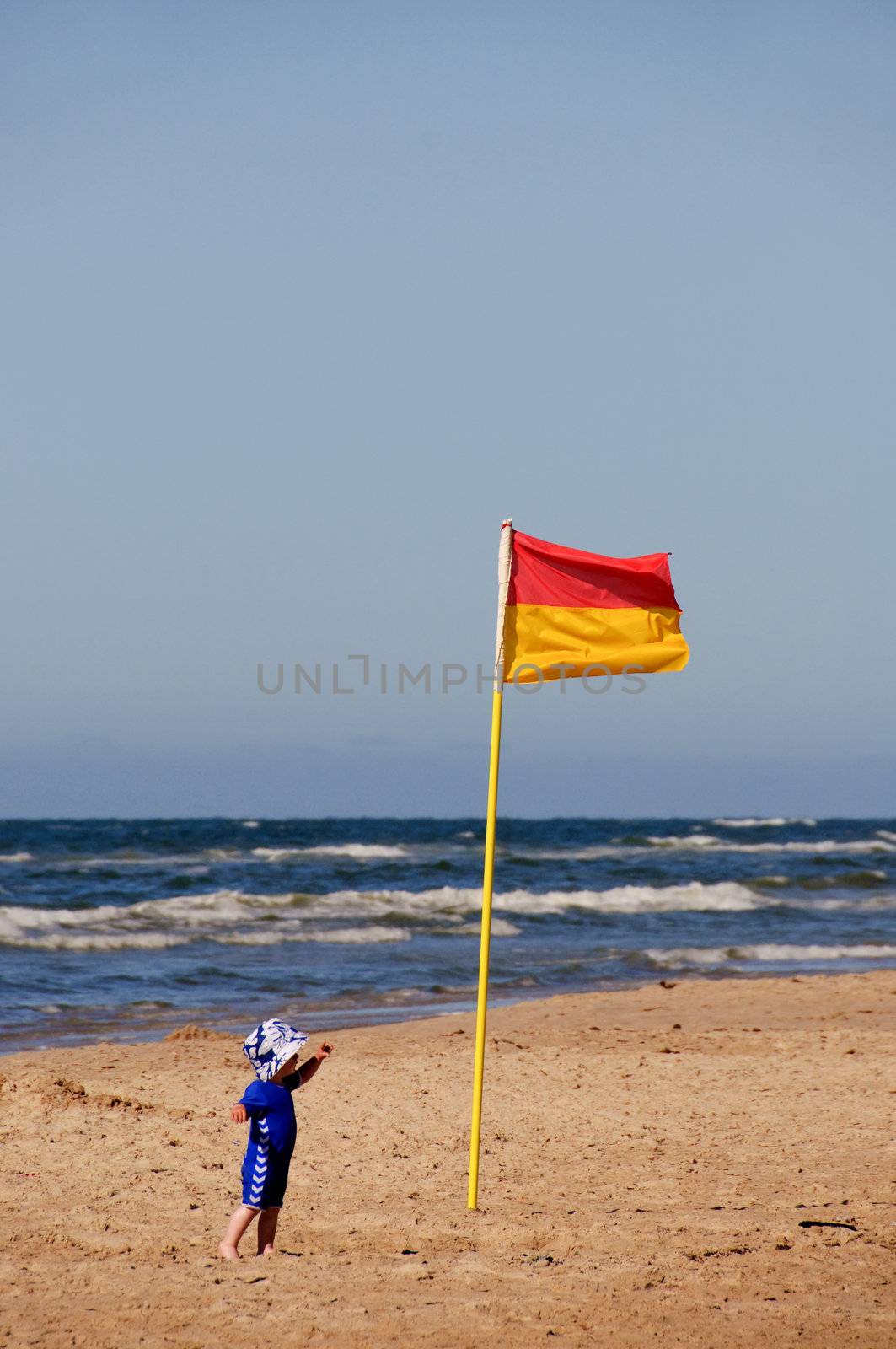 A small child pointing at the lifeguard flag