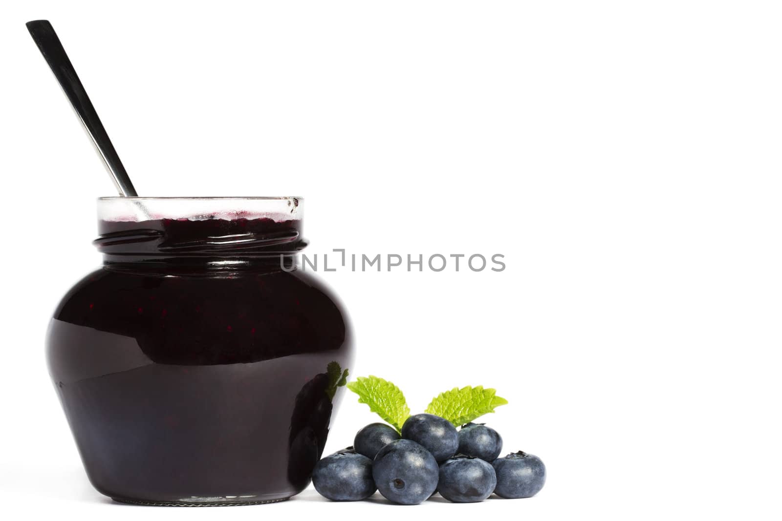 jam jar with blueberry jam a spoon and blueberries with a leaf melissa aside on white background