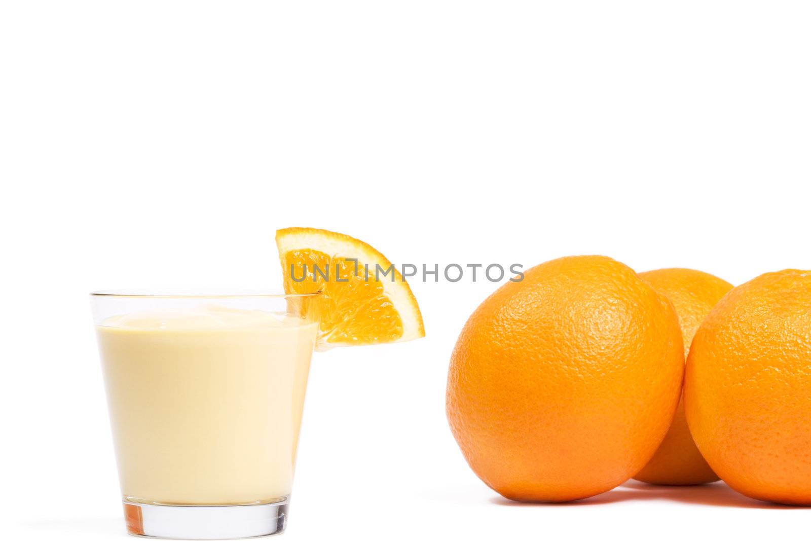 piece of a orange on a orange milkshake in front of oranges on white background