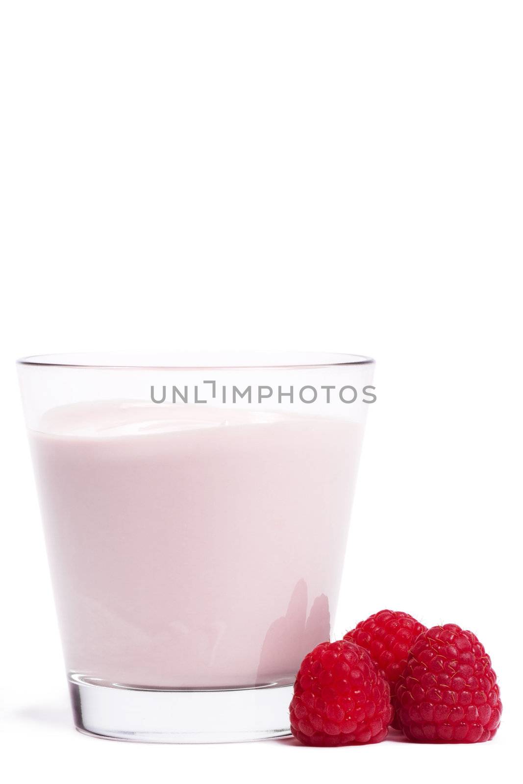 some raspberries near a milkshake on white background