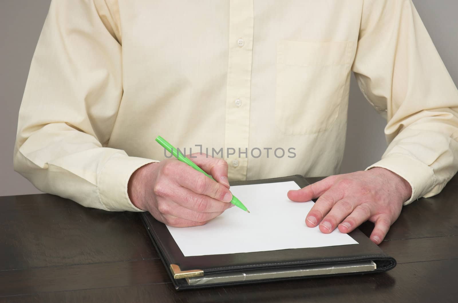 Man working at desk about to write notes.