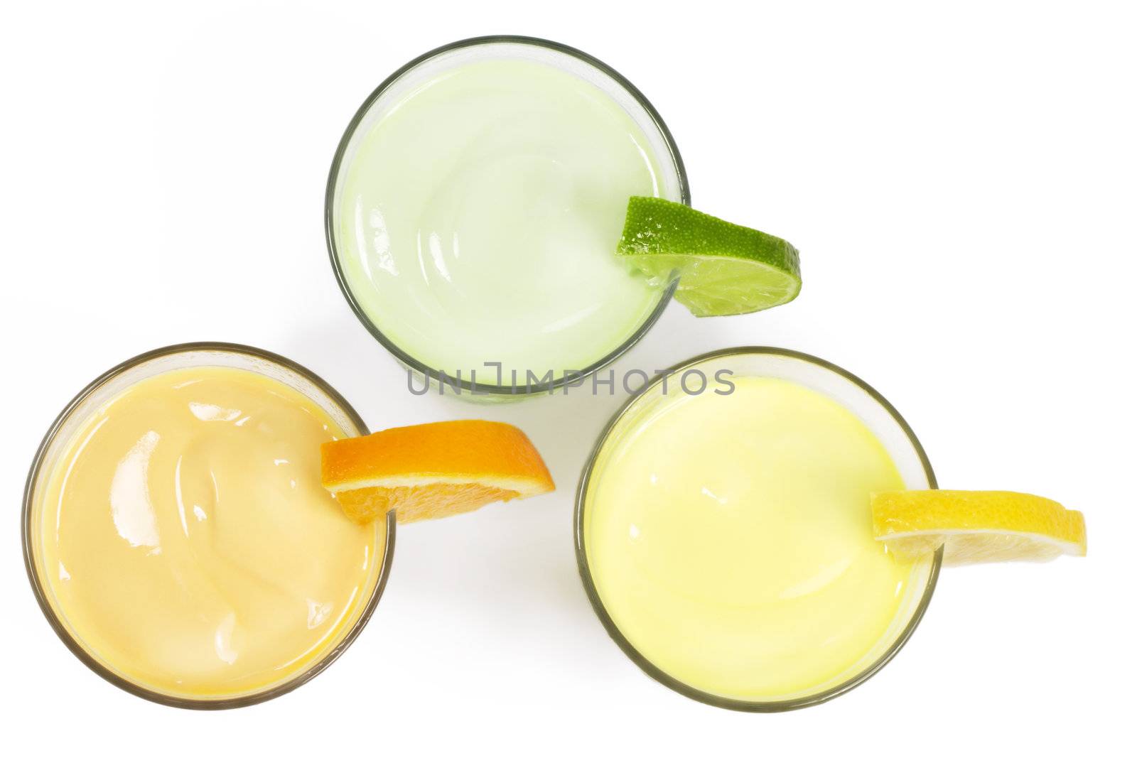 three cold citrus fruit milkshakes from top on white background