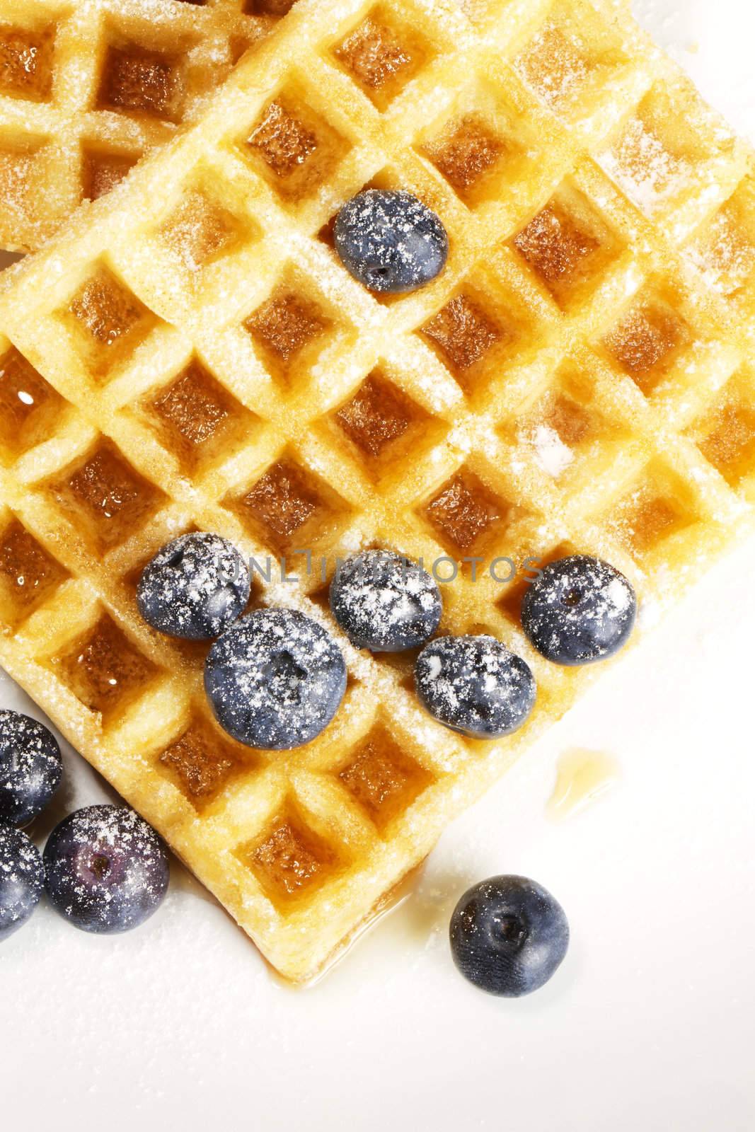 waffles with sugar covered blueberries and syrup from top on white background