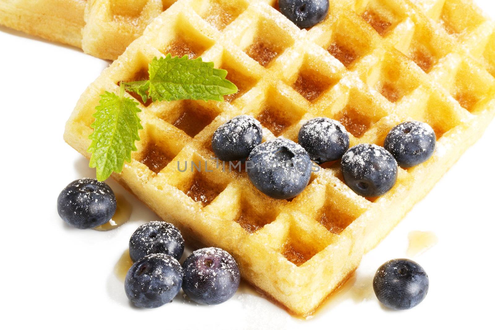 waffles with sugar covered blueberries melisss and syrup from top on white background