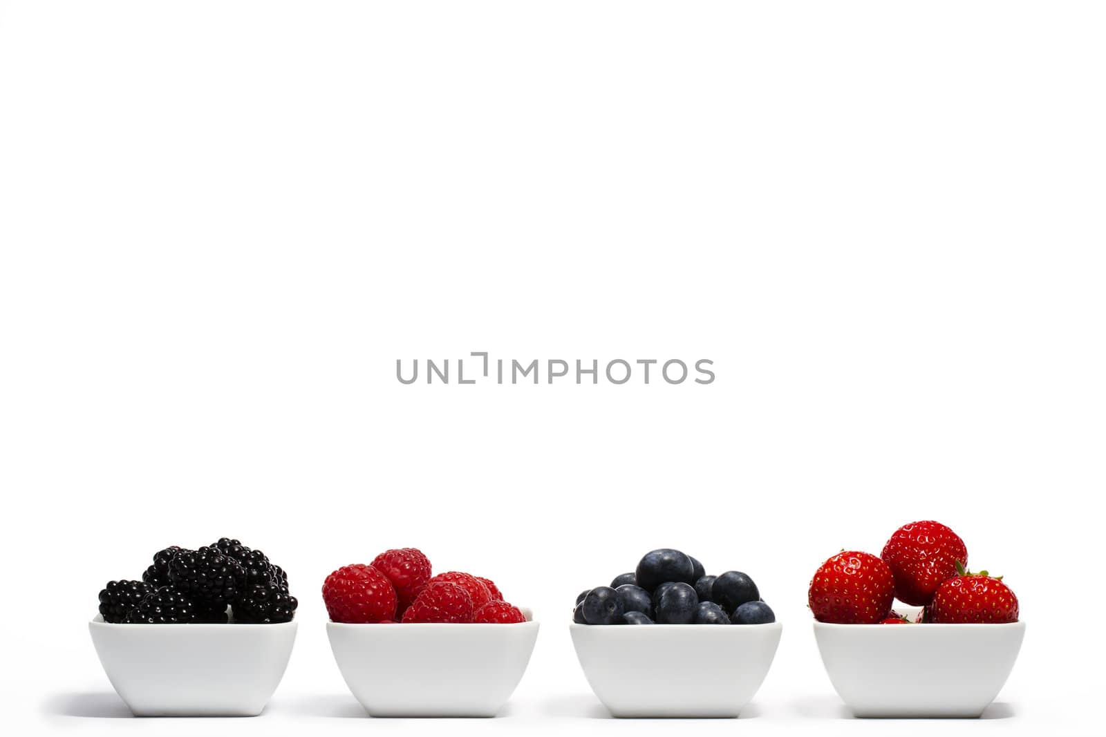 row of wild berries in bowls on white background