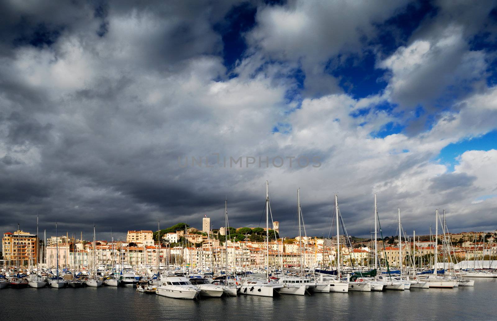 Images shows the Vieux Port (old port) in the city of Cannes, southern France, under a dramatic cloudy sky