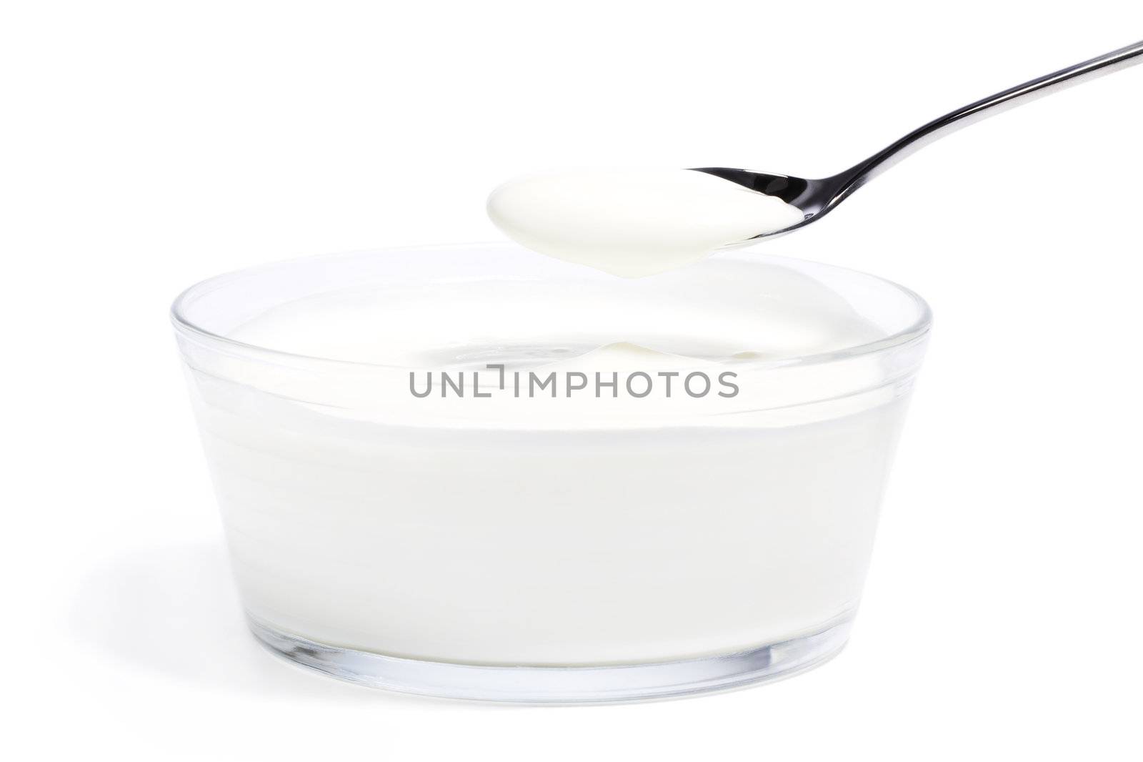 yogurt on a spoon over yogurt in a glass bowl on white background