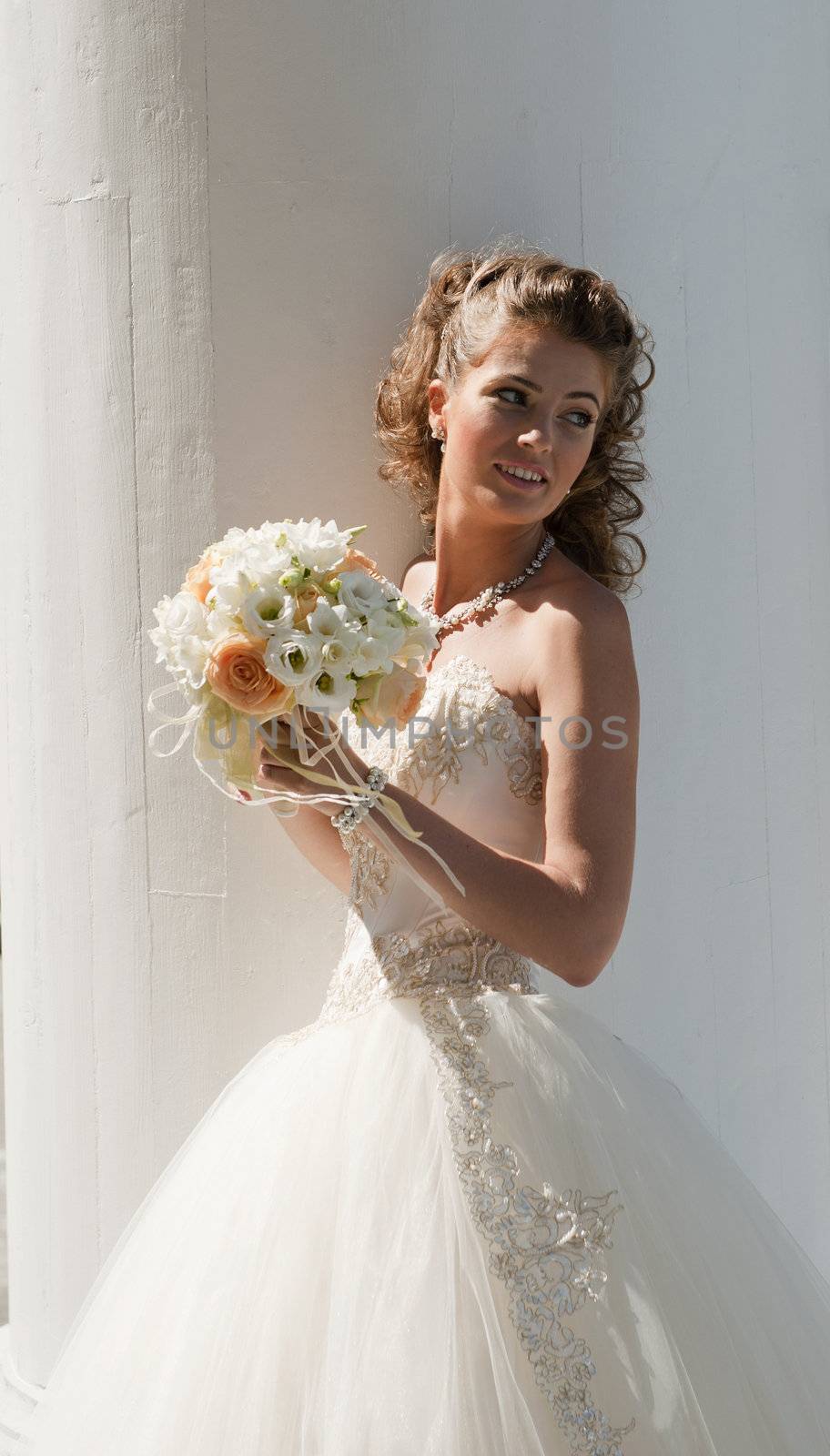 The bride with a bouquet. The bride in a wedding dress with a bouquet on the white.