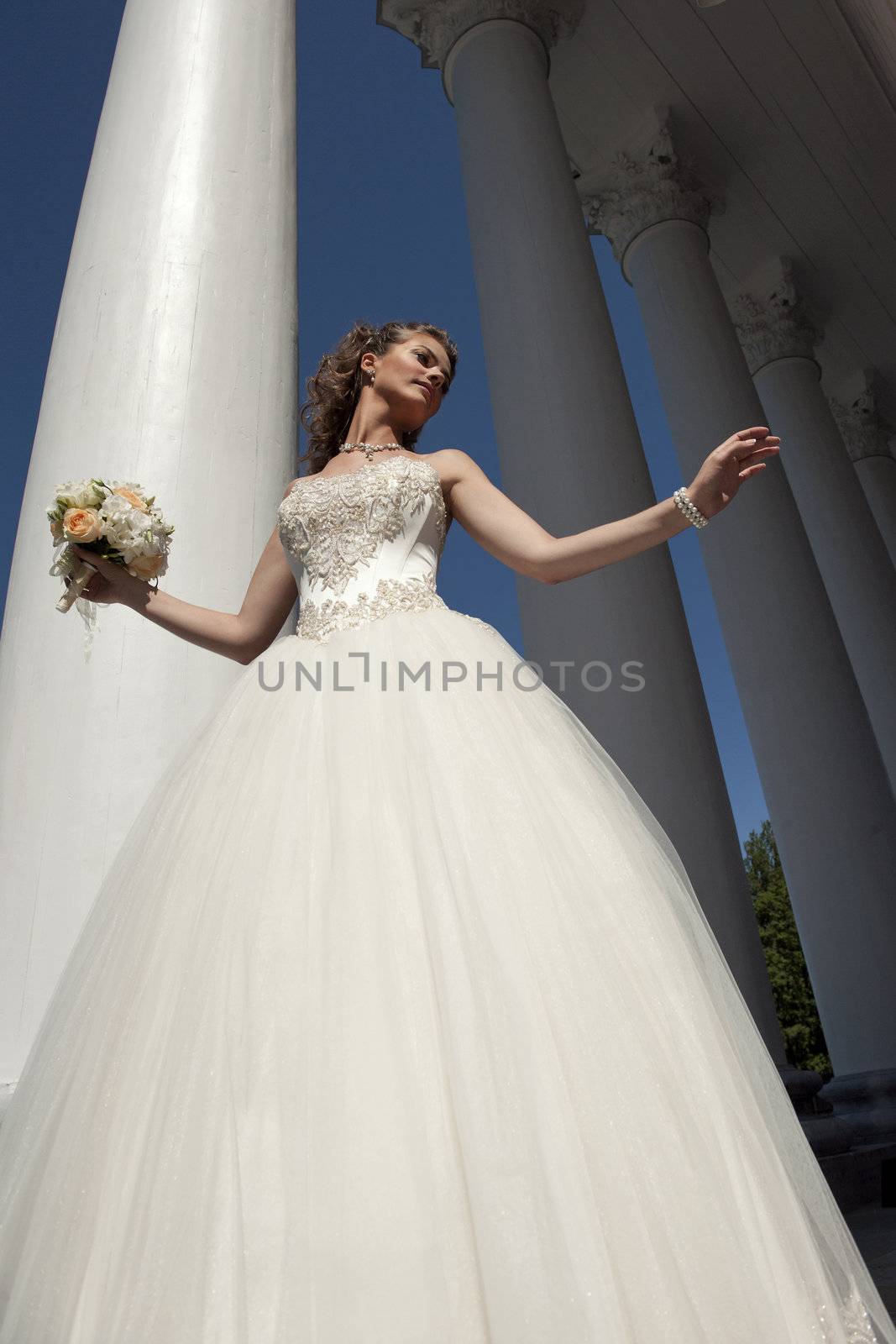 The bride with a bouquet at columns. by SURZ