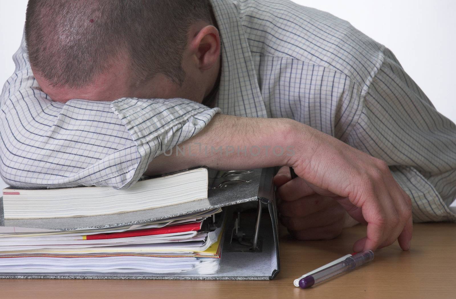 Male student slumped over his work after cramming for exams.