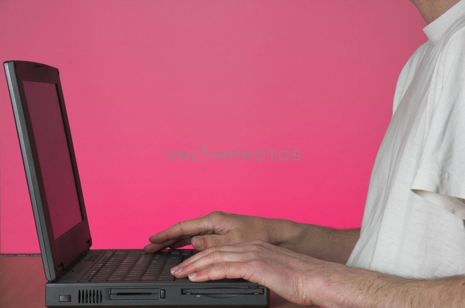 Man in white tshirt working on laptop computer.