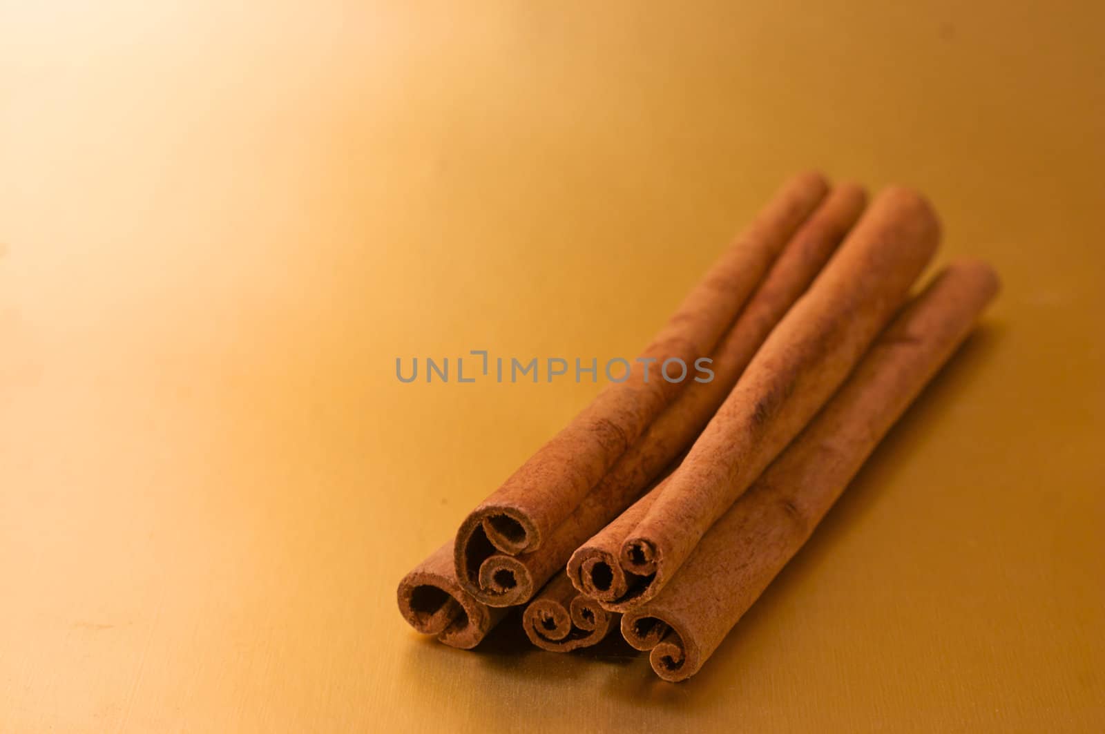 cinnamon sticks stacked on a gold background