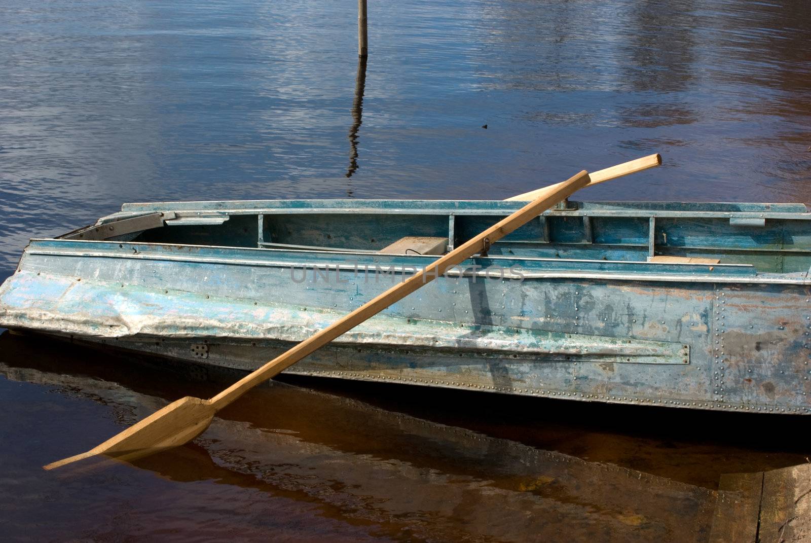 Boat with wooden oars on river bank.