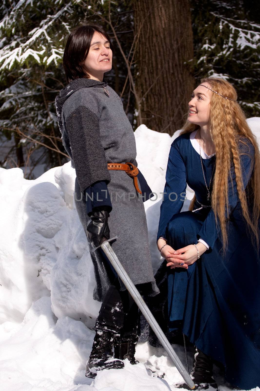 Two ladies in medieval dresses in winter forest
